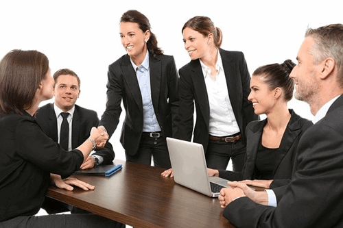 Five employees are having a meeting wearing suits.