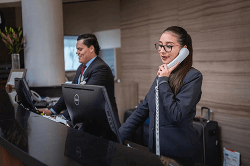 A woman talking on the phone at the front desk of a building.