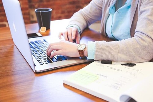 Employee making notes besides a laptop