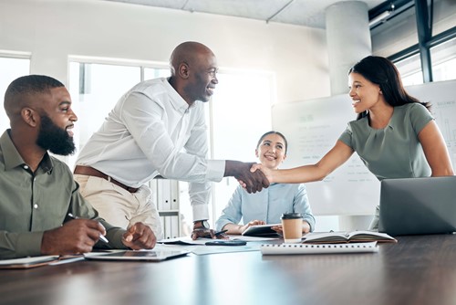 a male and female employee smiling and shaking hands