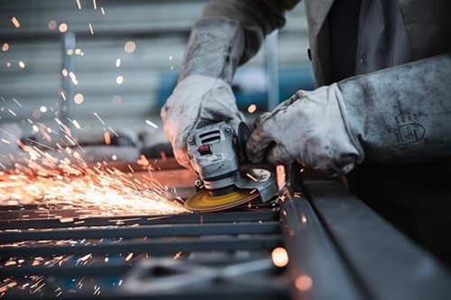 someone using a grinder on metal beams